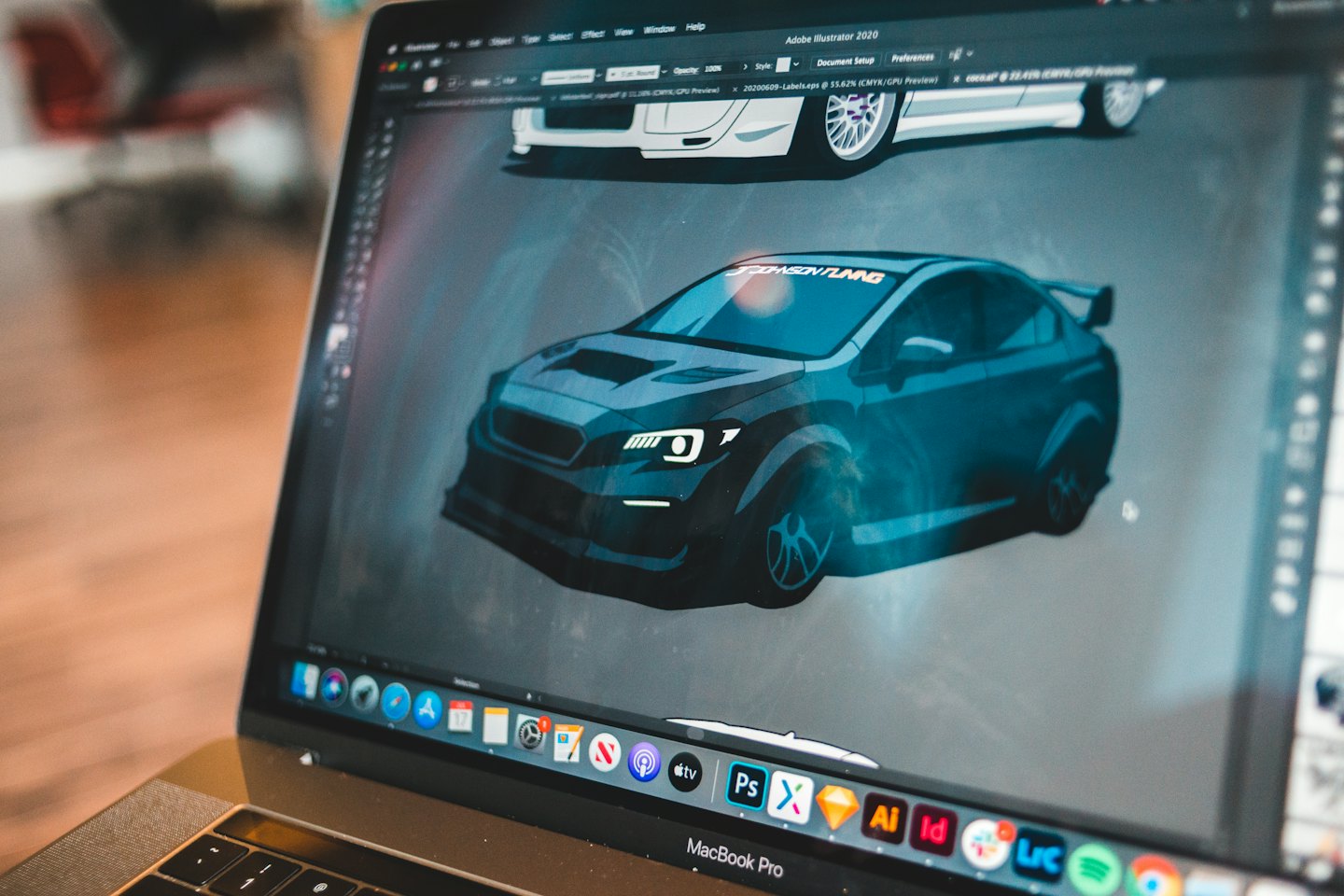 Software di graphic design su un laptop mostra due modelli di auto.